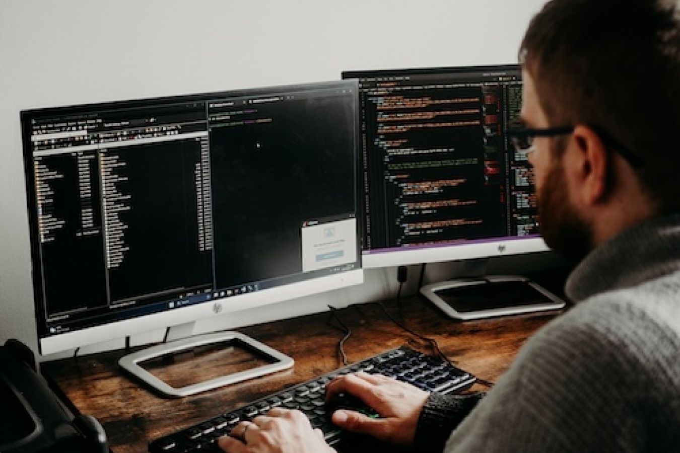 Person sitting at a computer with code at it. 