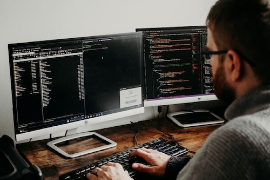 Person sitting at a computer with code at it. 