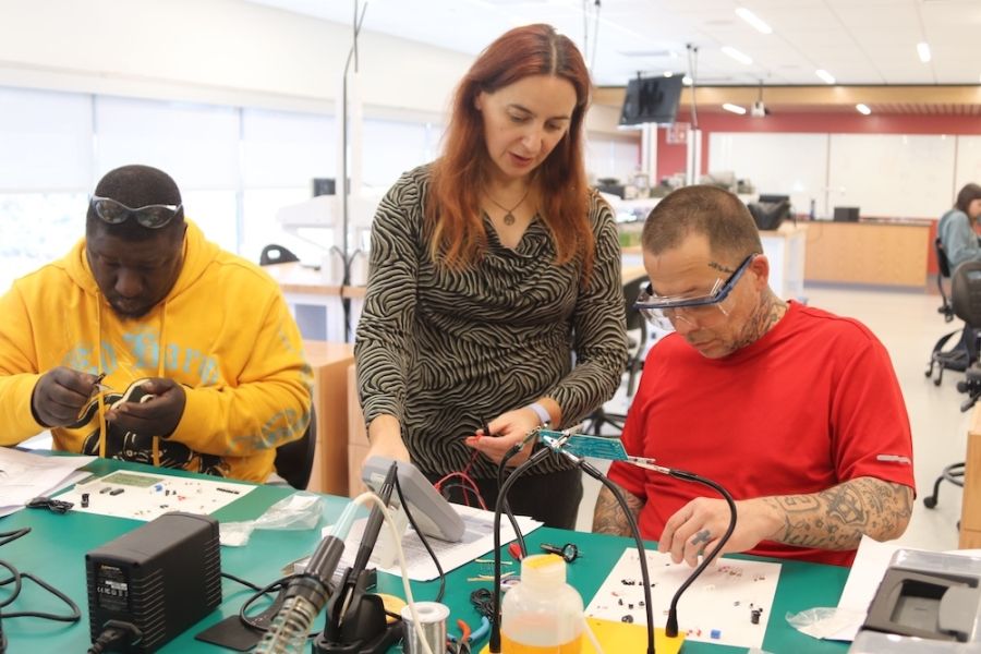 Three people at electrical equipment. 