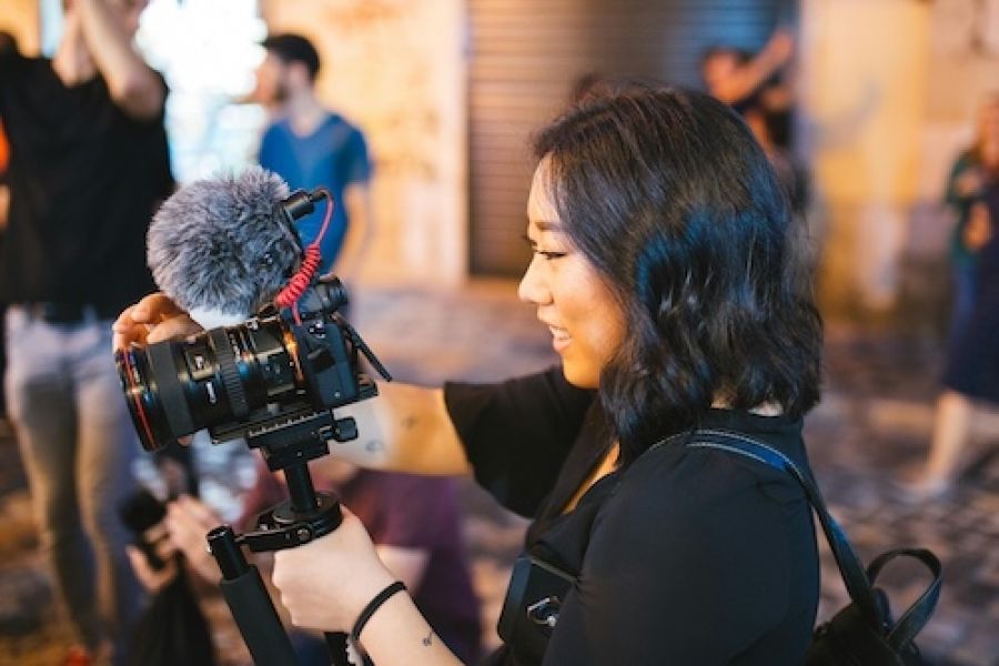 Woman holding a camera with a mic on it. 