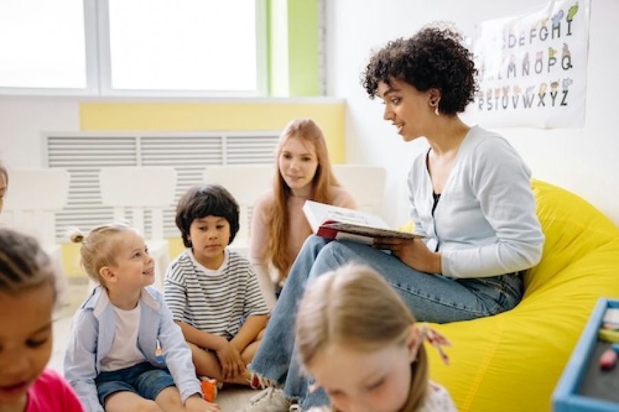 Woman reading to a classroom of kids. 
