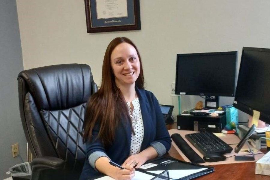 Patricia Schaap smiling and seated at a desk in an office. 