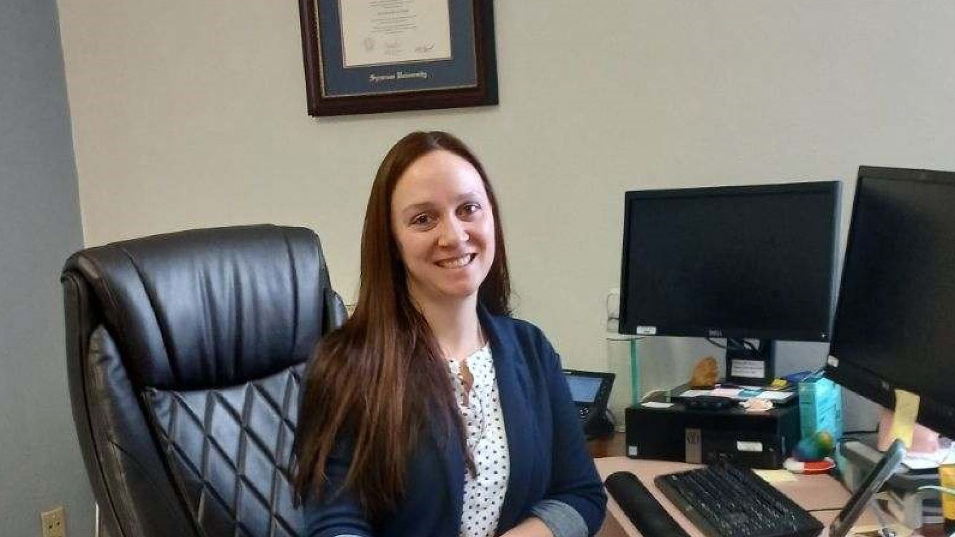 Patricia Schaap smiling and seated at a desk in an office. 