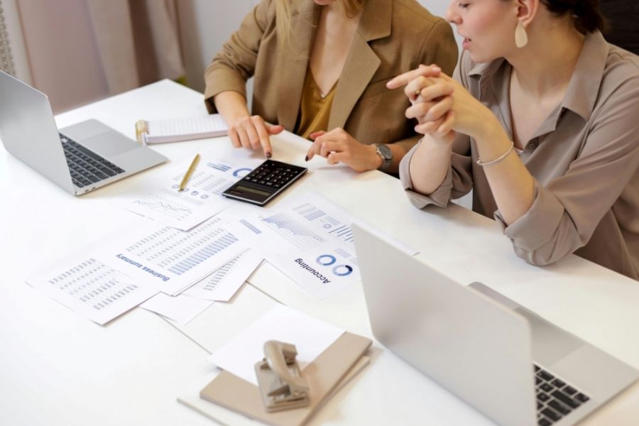 Two people looking over a bunch of papers on a table 