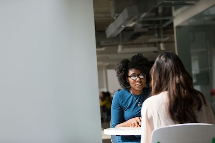 Two people sitting at a table and talking. 